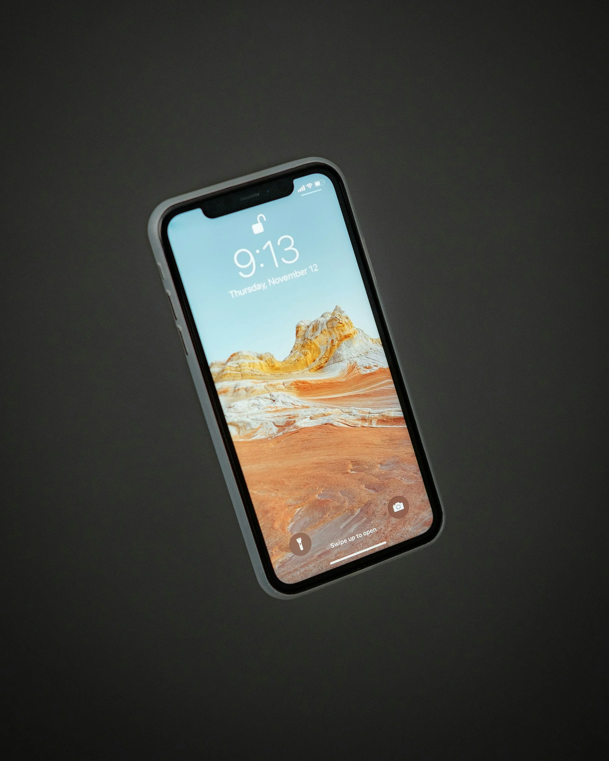iPhone with desert mountain landscape on the lock screen, black background