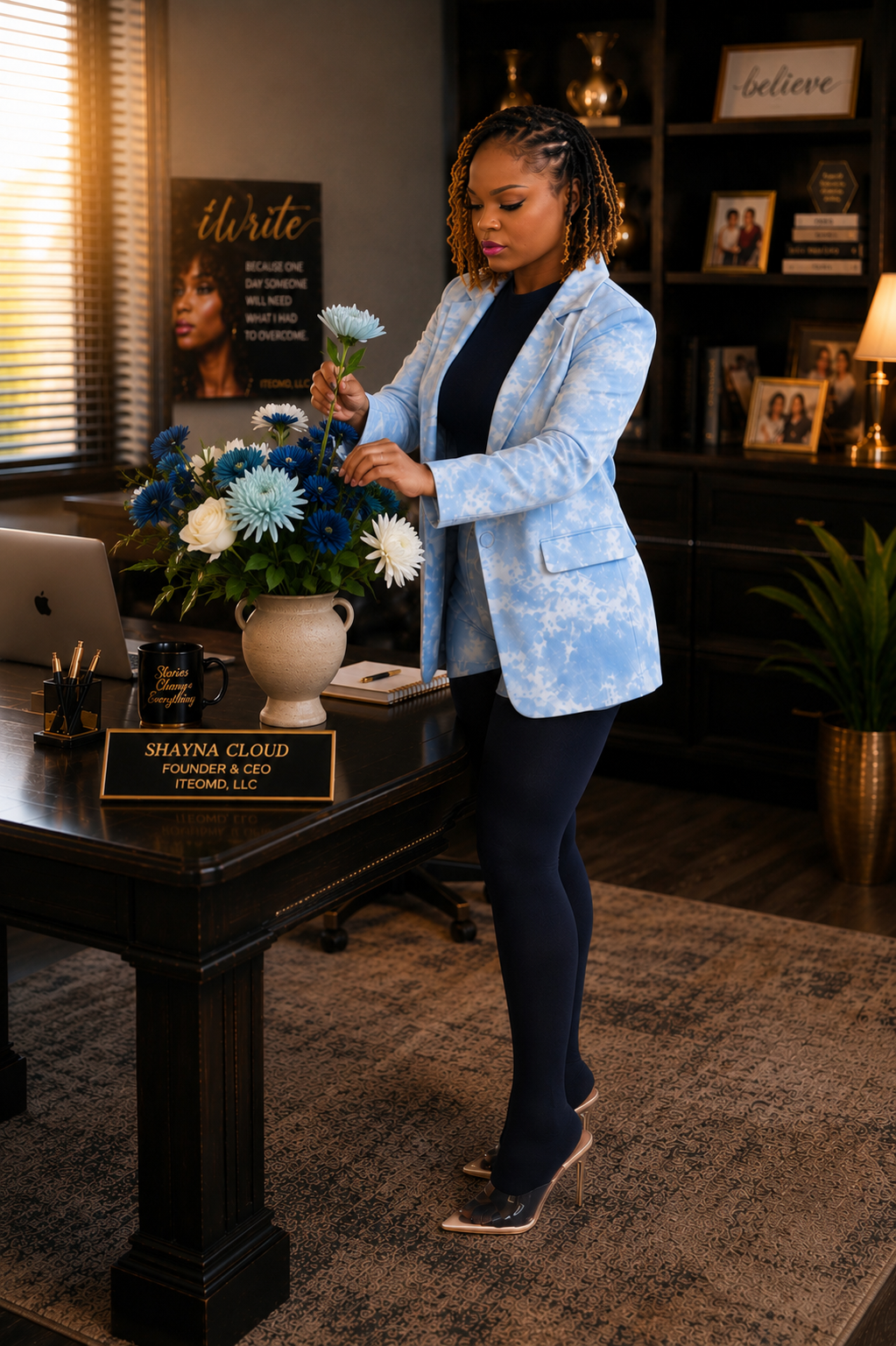 Shayna Cloud, founder and storyteller of ITEOMD, arranging a bouquet of blue, white, and light blue flowers in a beige vase in an office or home office setting.