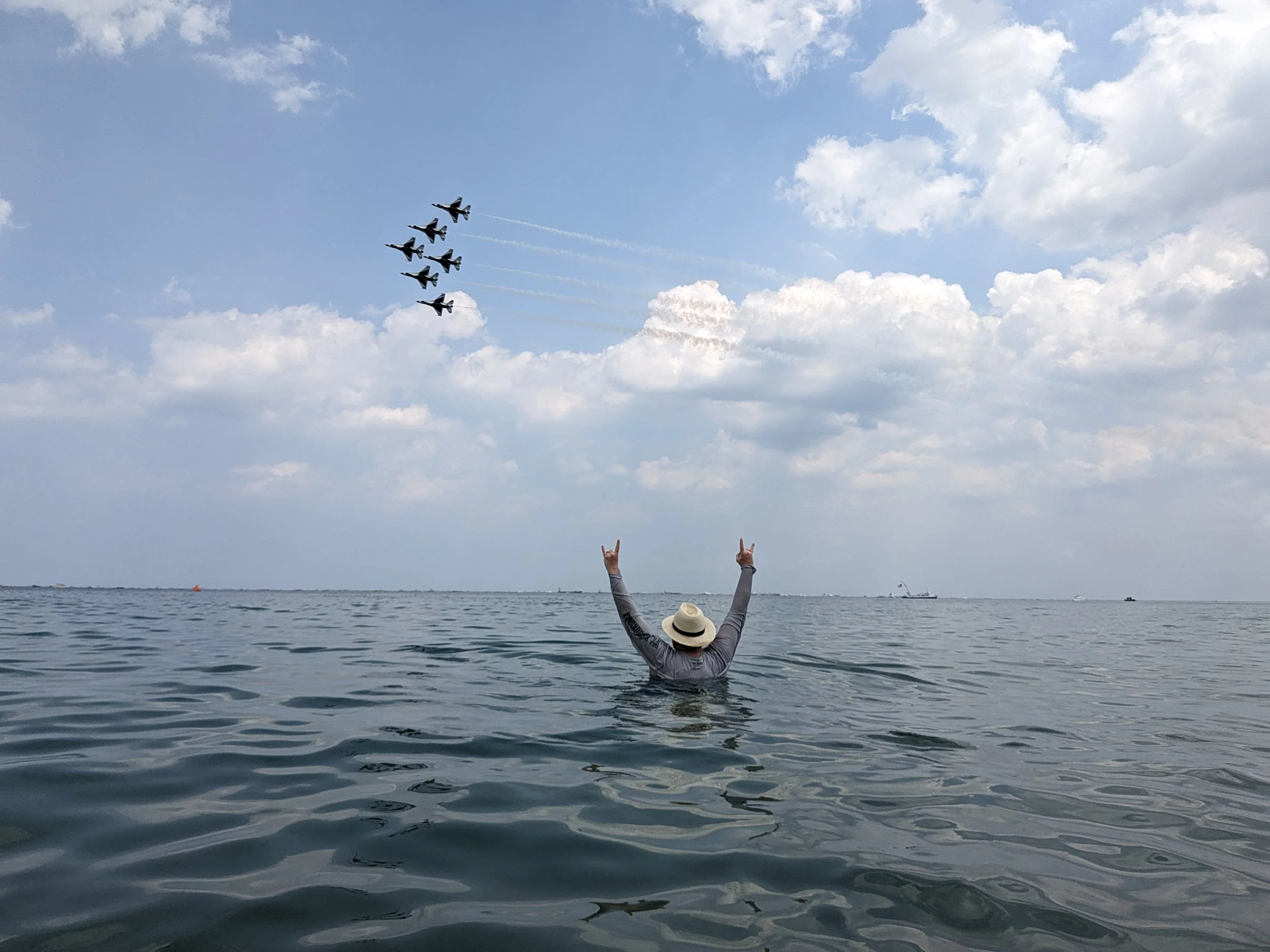 Ryan in ocean looking up at 6 fighter jets in formation