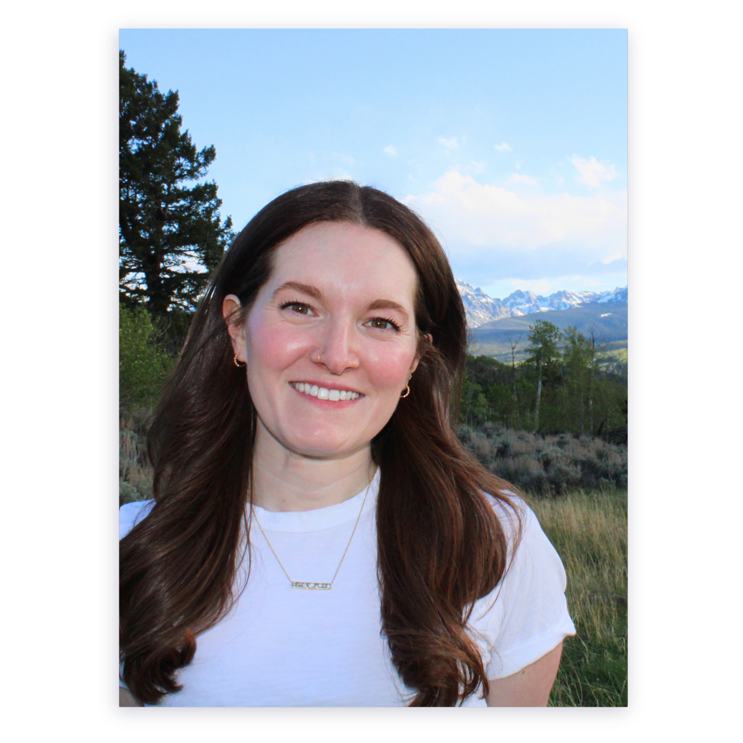 Laura Landrum, EMDR therapist in Summit County, Colorado, smiling outdoors with mountains, trees, and a blue sky in the background.