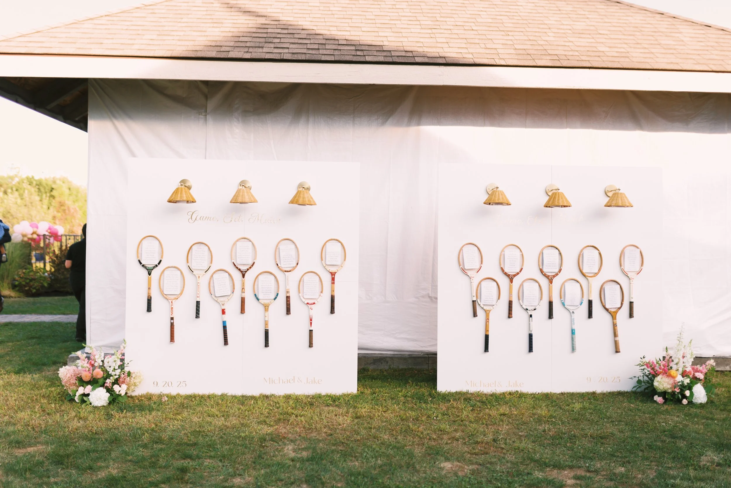 Wedding display with tennis racquets attached to white boards, decorated with flowers at the base, celebrating a wedding for Michael and Jake on September 20, 2025.