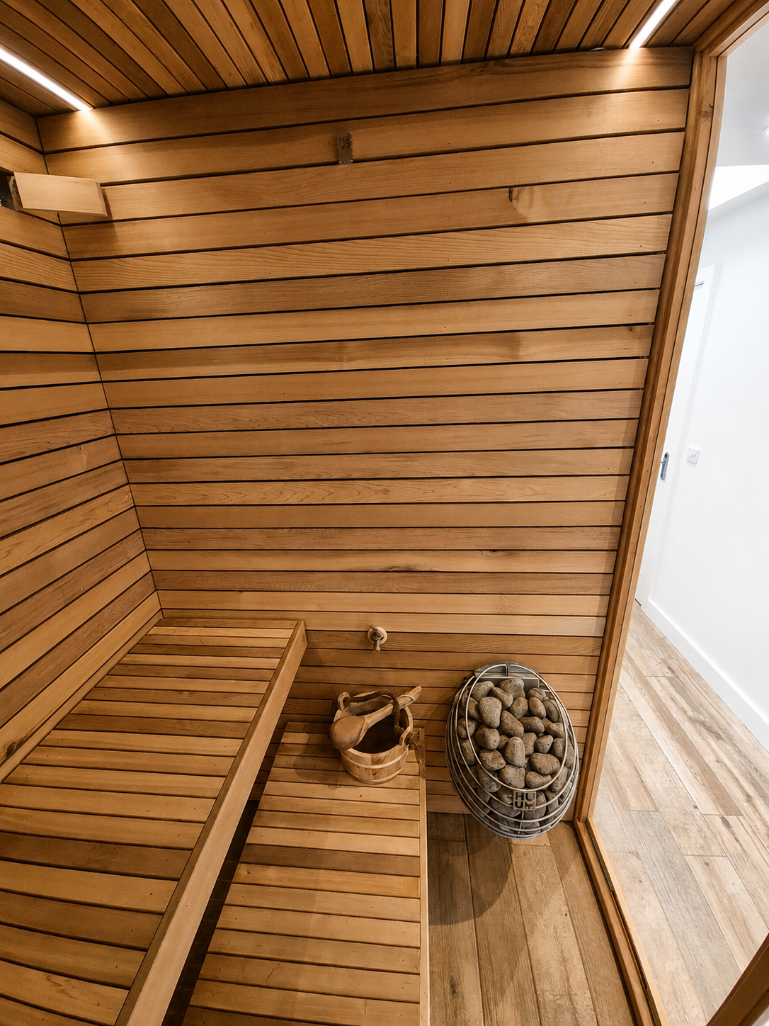 Interior of a wooden sauna with benches and a heater filled with stones.