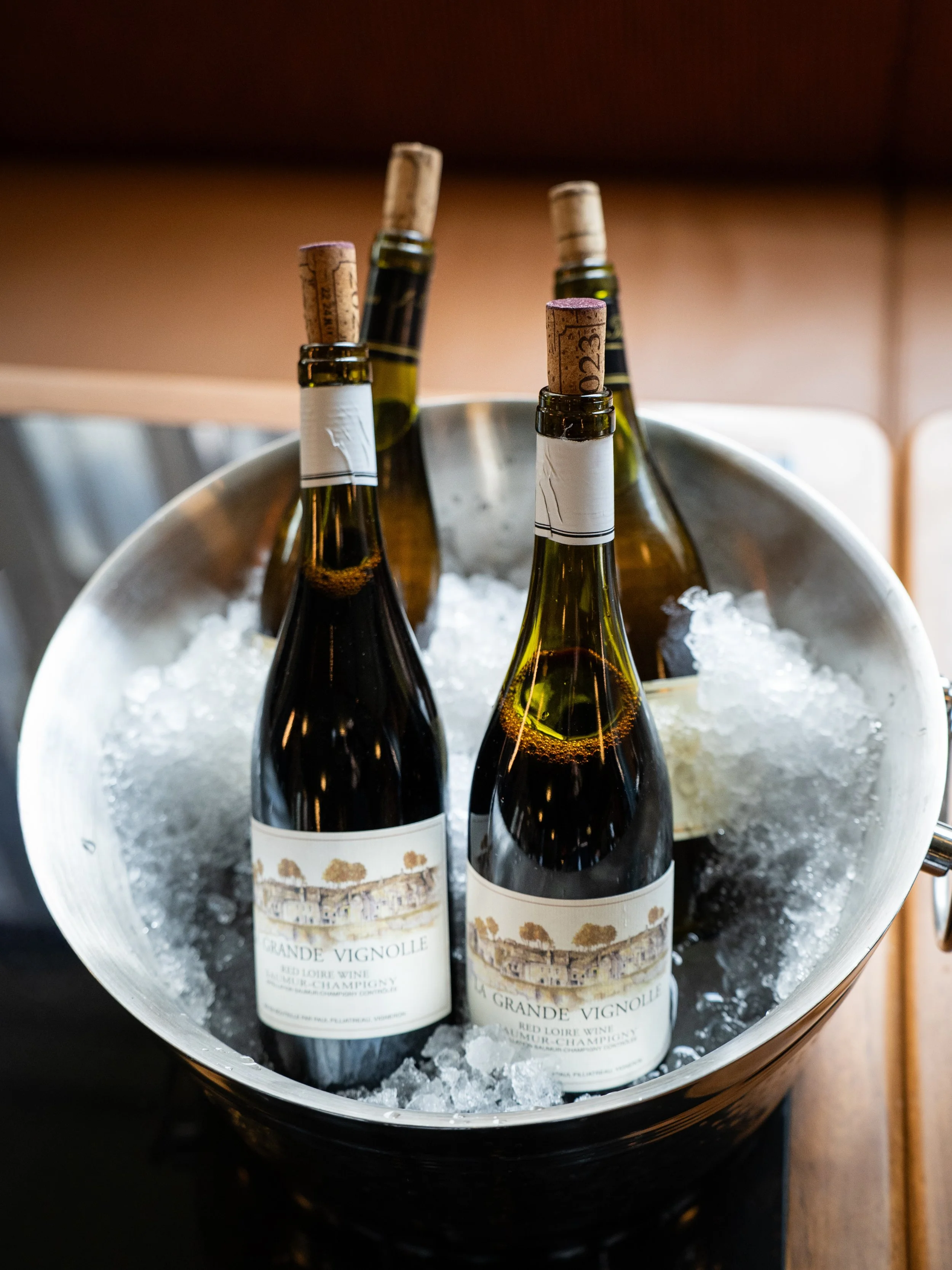 Four bottles of red wine in a metal ice bucket filled with ice