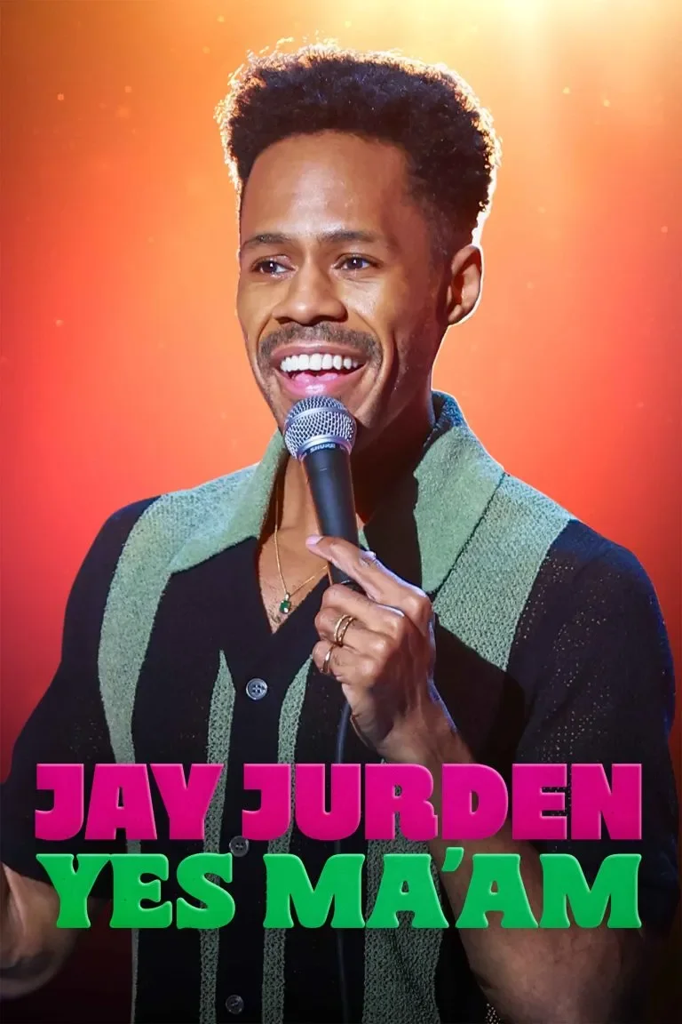 A man with short curly hair, smiling and holding a microphone, wearing a black shirt with green and black vertical striped pattern. The background is orange-yellow with light bokeh effects. Text at the bottom reads "JAY JURDEN YES M'AM" in pink and green letters.