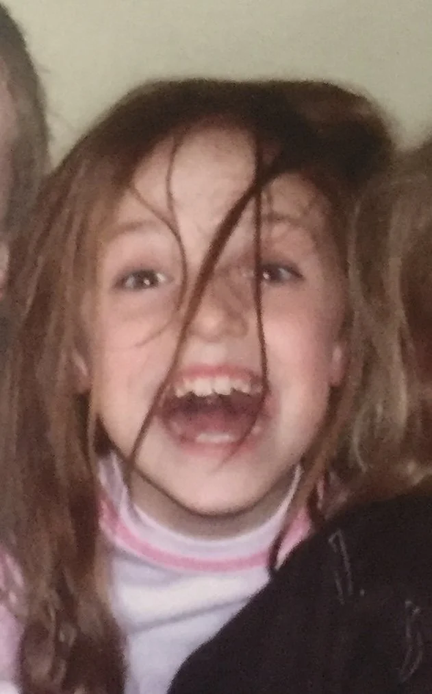 Child with crazy hair smiling widely.