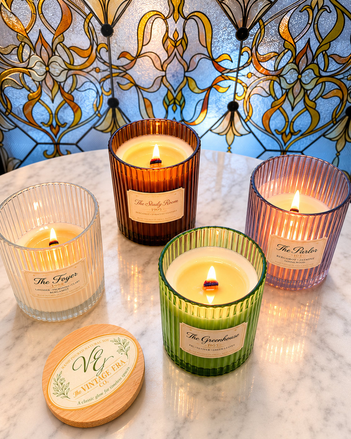 Four lit candles in colorful glass containers placed on a white marble table with an ornate stained glass window in the background.