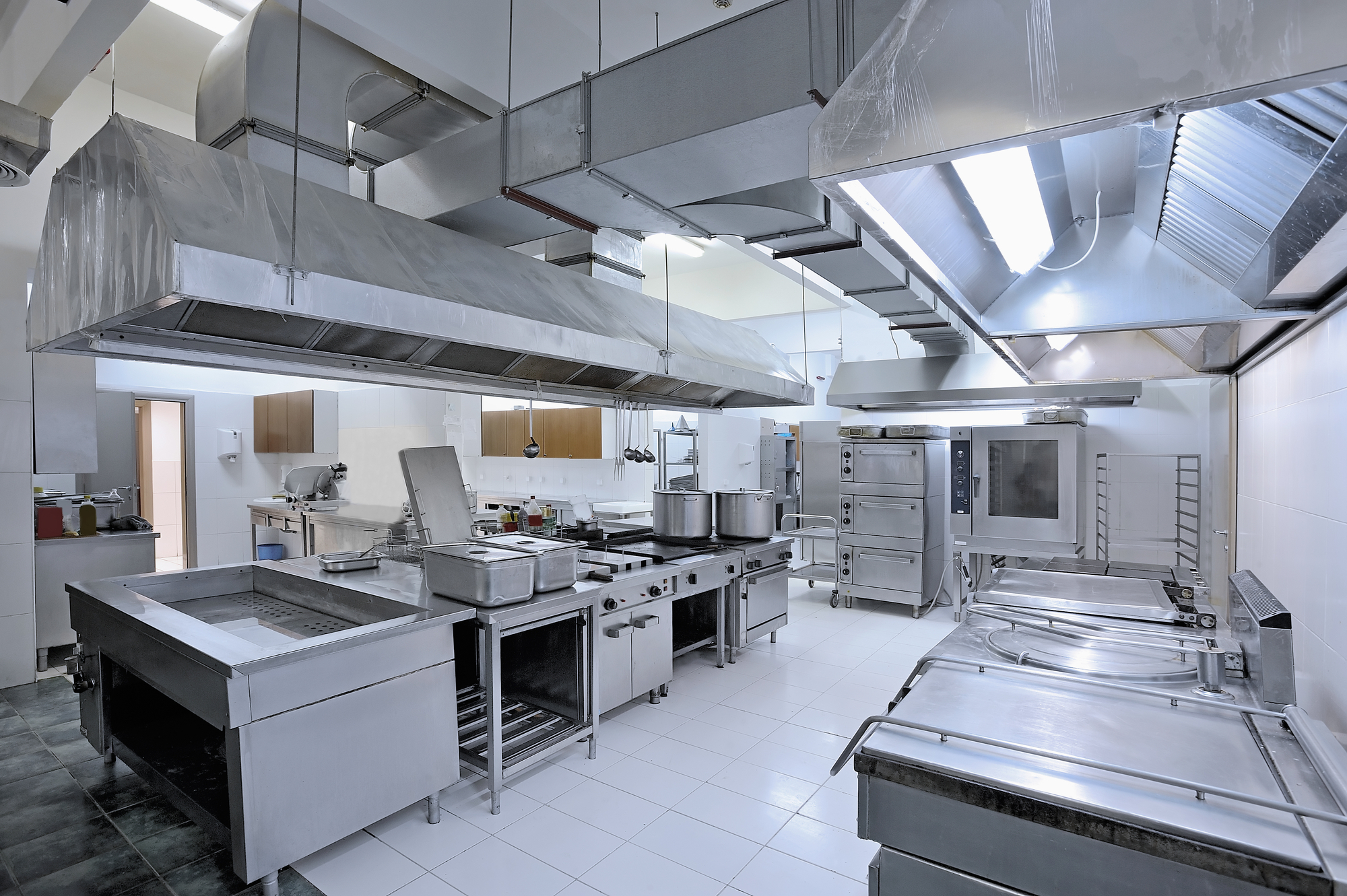 Commercial industrial kitchen with stainless steel appliances and countertops.