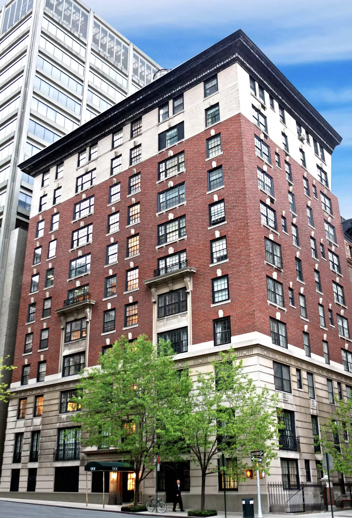 A tall, multi-story building with a red brick facade, large windows, and ornate decorative elements around the windows and at the roofline, located on a city street with trees and a sidewalk.