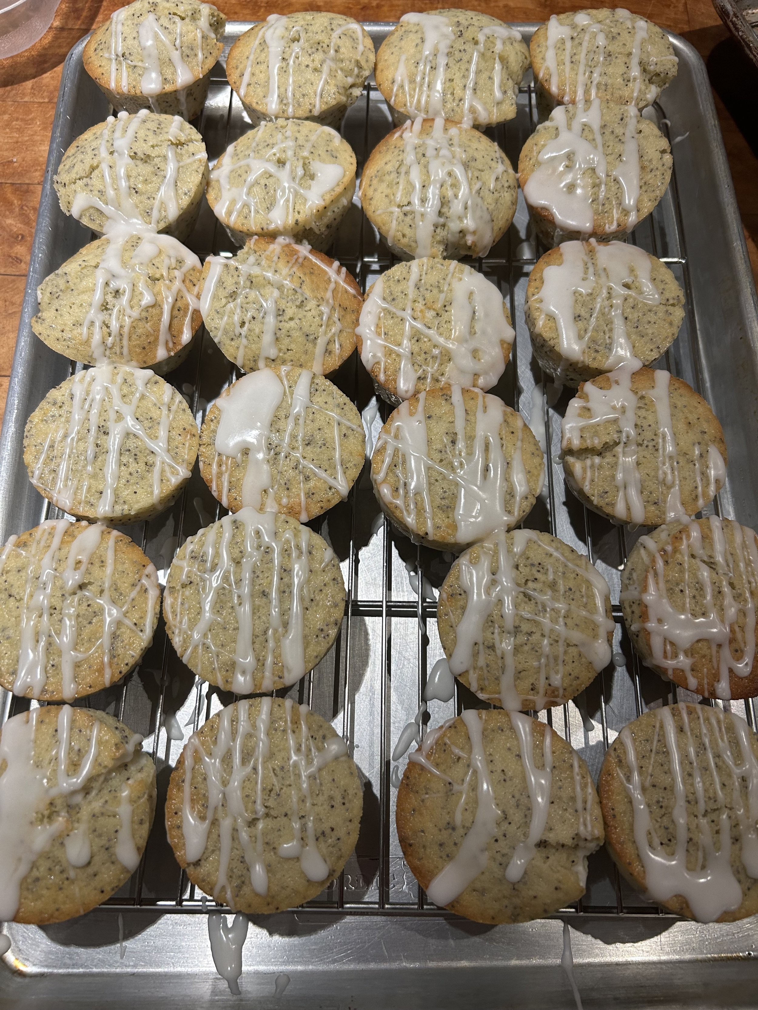 Cookies topped with white icing, placed on a cooling rack on a metal tray.