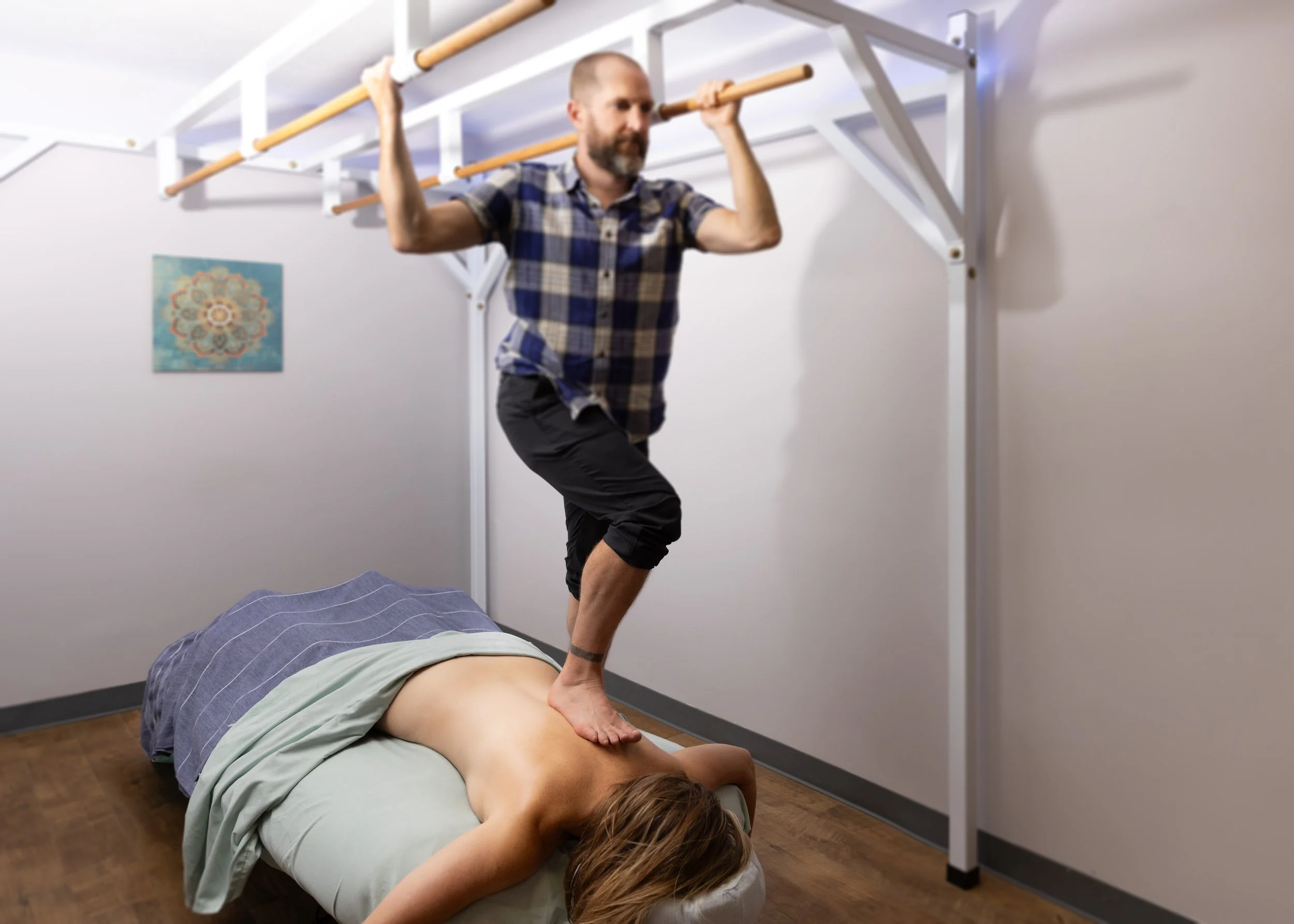 A man performing acupuncture on a woman lying face down on a massage table in a clinic or therapy room.