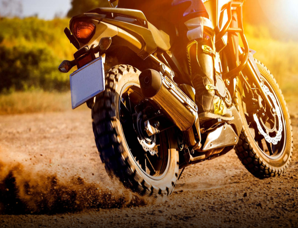 A motorcycle riding on a dirt trail during sunset or sunrise.