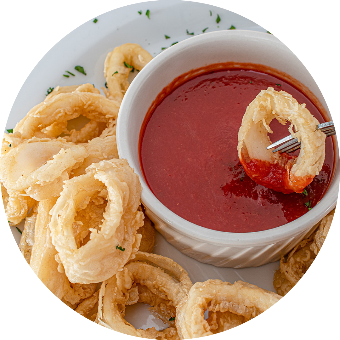 Bowl of marinara sauce with fried calamari and parsley on a white plate.