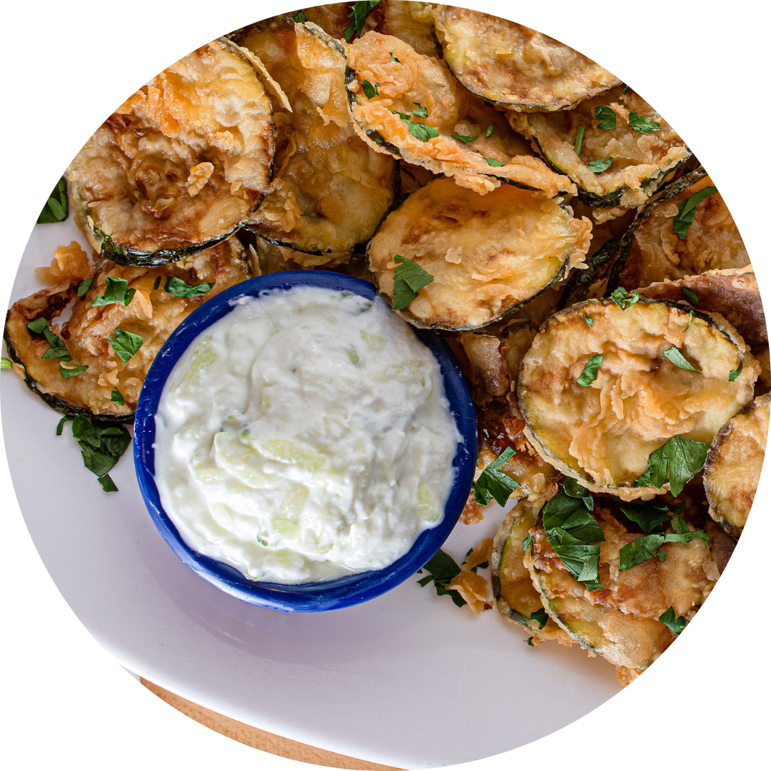 Baked zucchini slices topped with herbs served with a side of creamy tzatziki dip.