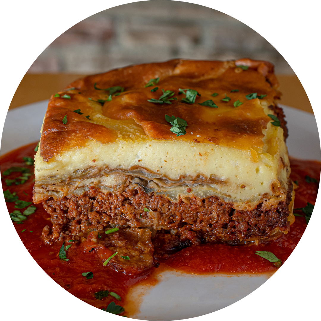 A slice of shepherd's pie with a layer of mashed potatoes on top, garnished with chopped parsley, served with a side of tomato sauce.