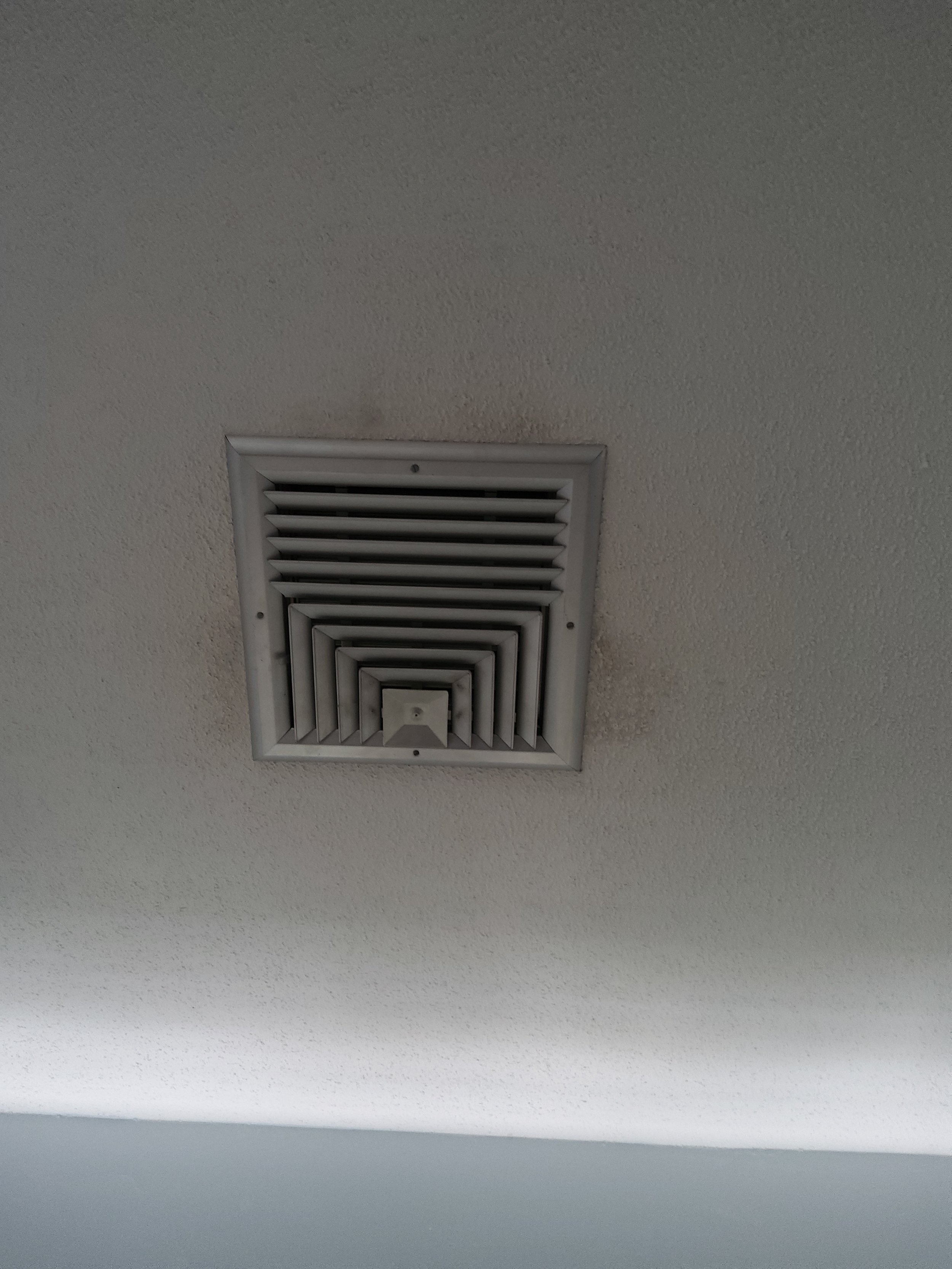 Ceiling air vent on a textured white ceiling.