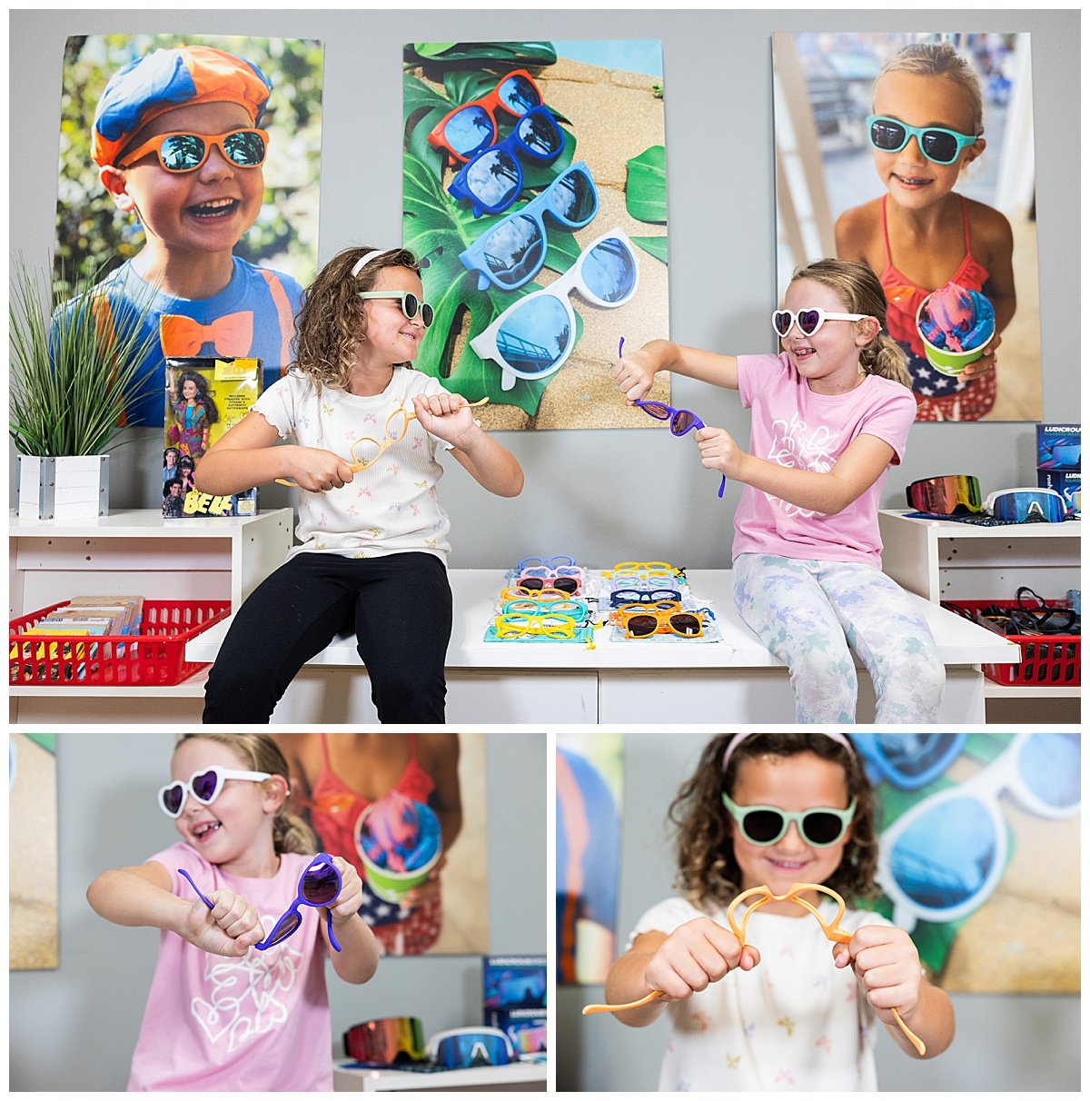 Two young girls trying on colorful sunglasses at a sunglasses store with large posters of children wearing sunglasses on the wall behind them.
