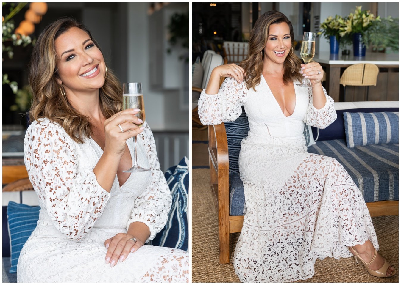 A woman in a white lace dress holding a glass of champagne, smiling in an indoor setting with decorative pillows and plants.