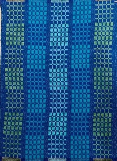 Close-up of a colorful woven fabric with vertical stripes and geometric patterns in shades of blue, green, and light blue.