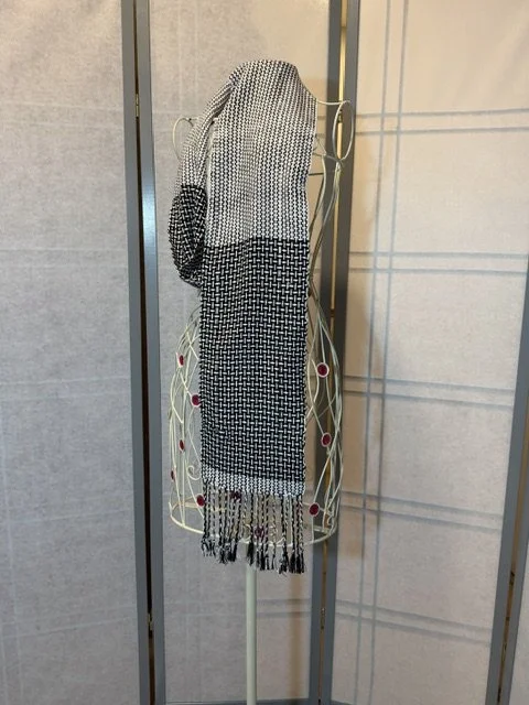 Woven black and white scarf draped over a decorative metal mannequin stand.