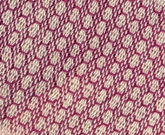 Close-up of a woven fabric with a pink and beige pattern.