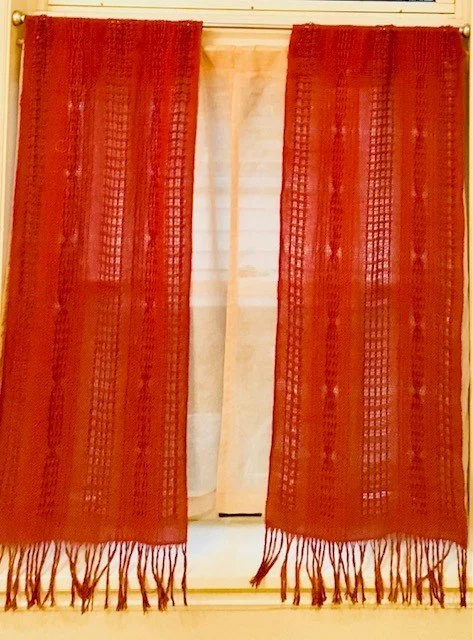 Red curtains with fringes hanging in front of a window