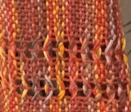 Close-up of multicolored woven fabric with orange, yellow, pink, blue, and purple threads.