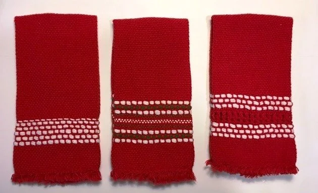 Three red towels with white dotted stripes laid out flat on a white surface.