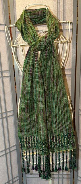 Green patterned scarf draped over a white wire mannequin stand.