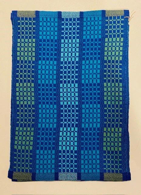 Colorful woven textile with vertical blue and green striped geometric patterns.