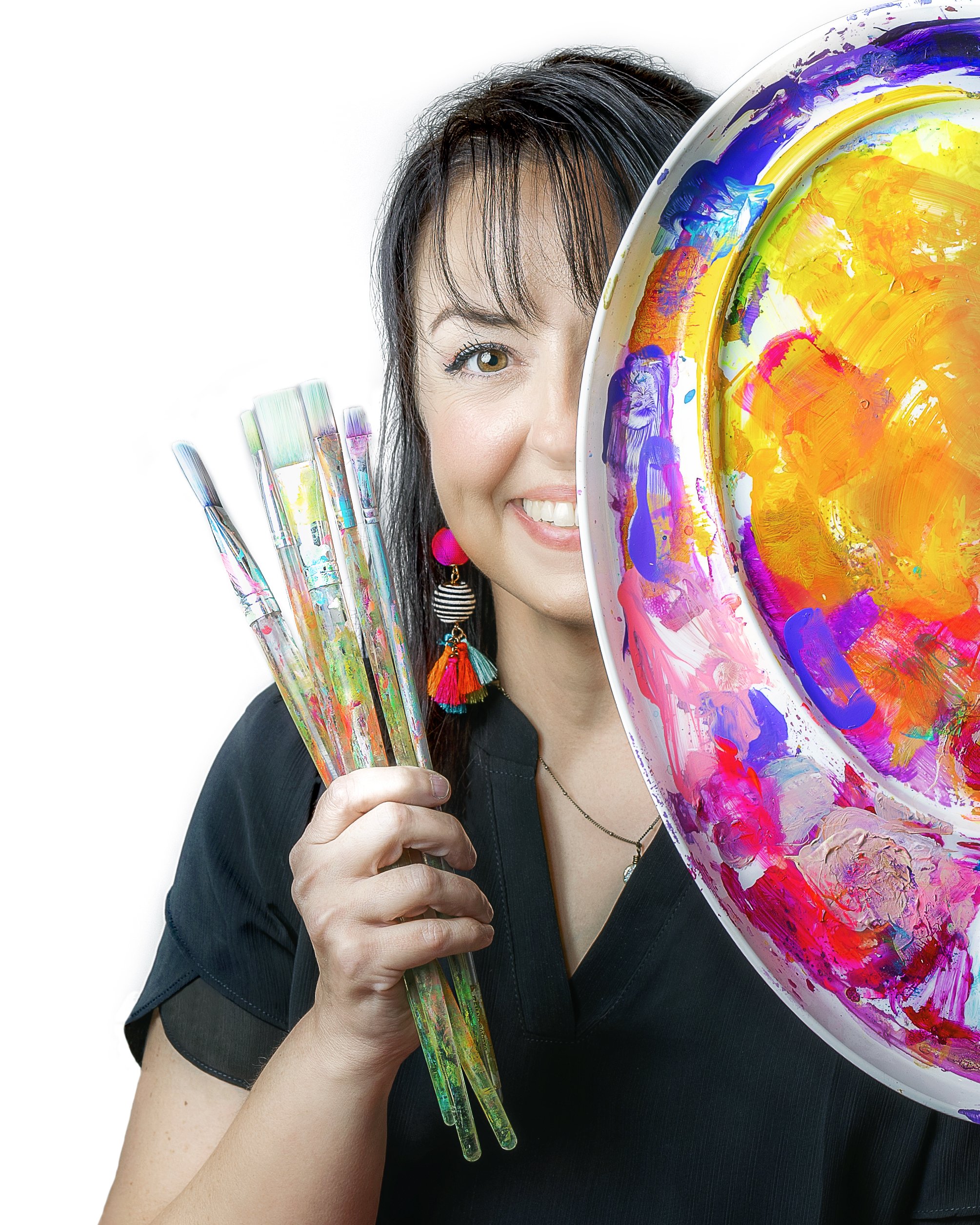 A woman with dark hair and earrings holding paintbrushes and a large abstract colorful palette.