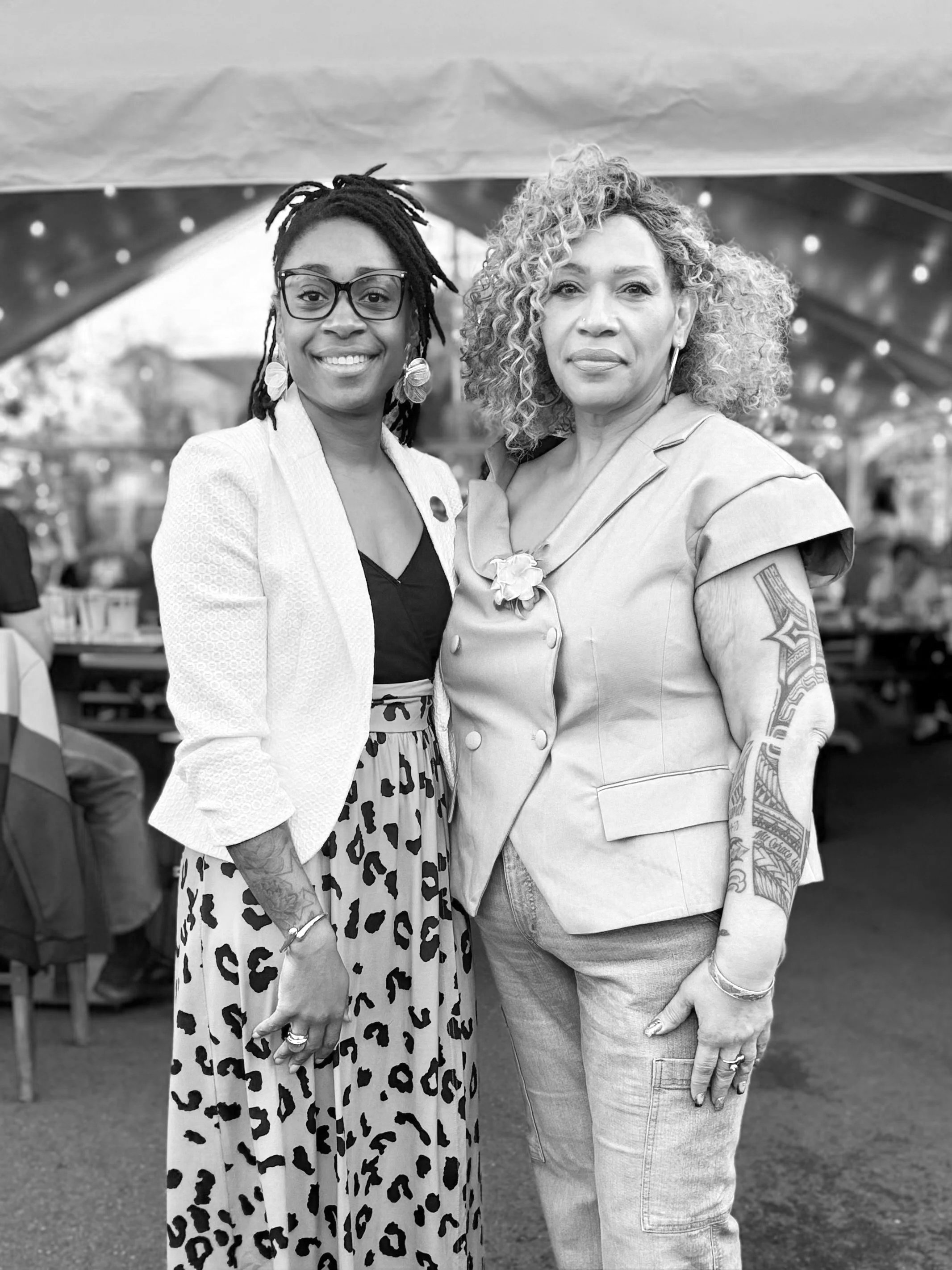 Black Ember House founder Rashida Saunders and Board Chair Kim Dixon smiling together at an outdoor event.