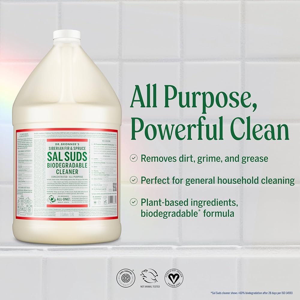 A large jug of Dr. Bronner's Siberian Fir & Spruce Sal Suds biodegradable cleaner next to text on a white tiled wall. The text reads: 'All Purpose, Powerful Clean' and lists features such as removing dirt, grime, and grease, being perfect for general household cleaning, and containing plant-based, biodegradable ingredients.