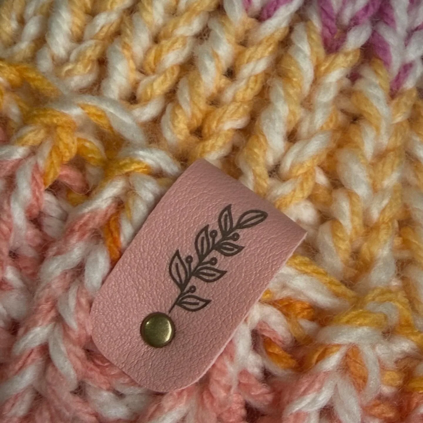 Close-up of a multicolored, thick, braided, chunky yarn with a pink tag attached.