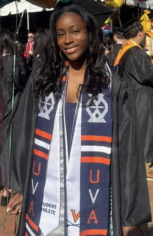 Young woman at graduation ceremony wearing cap, gown, and scarf with university colors and logo, smiling at camera.