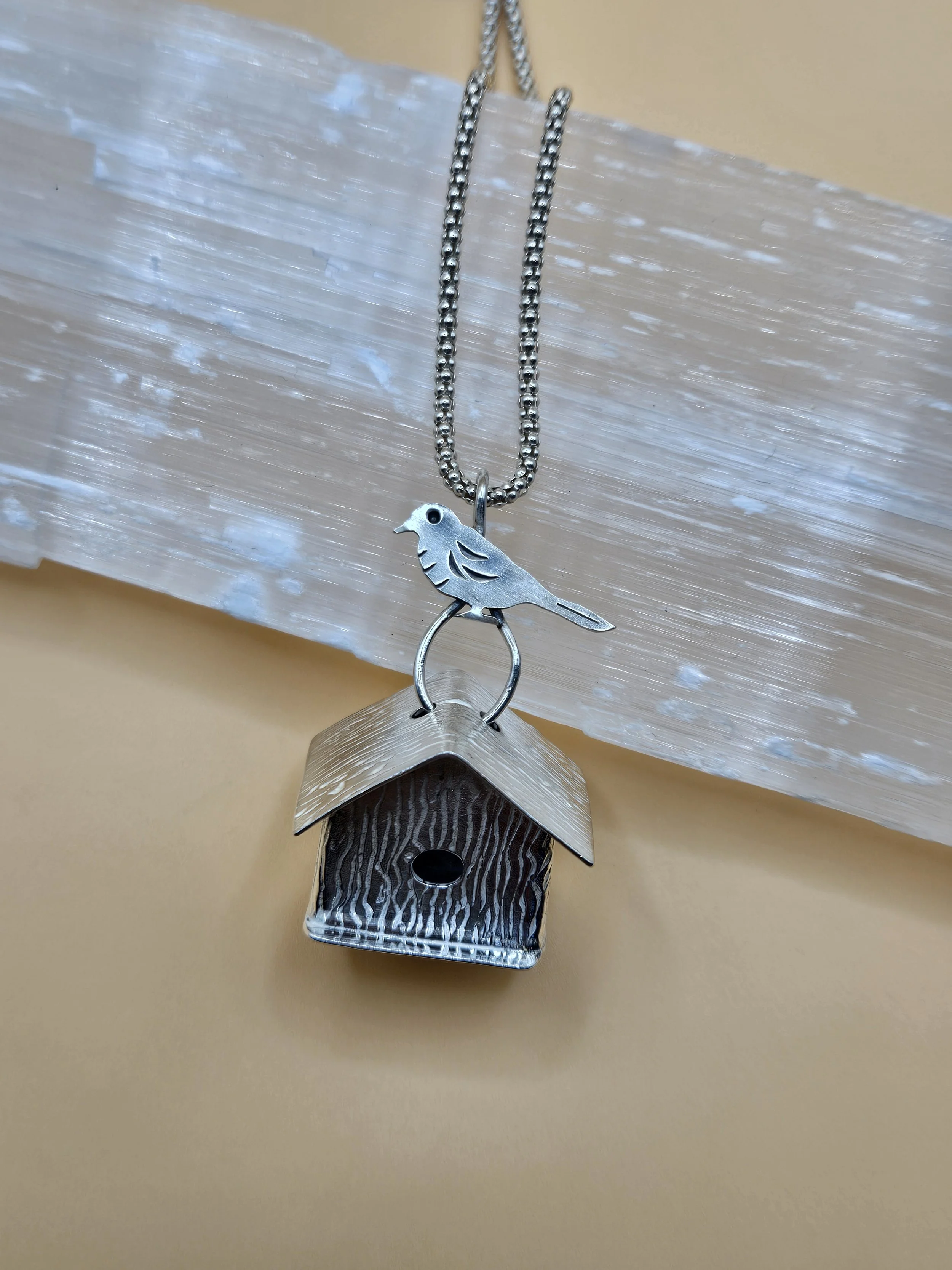 Sterling silver bird house pendant with a silver bird on the bail.