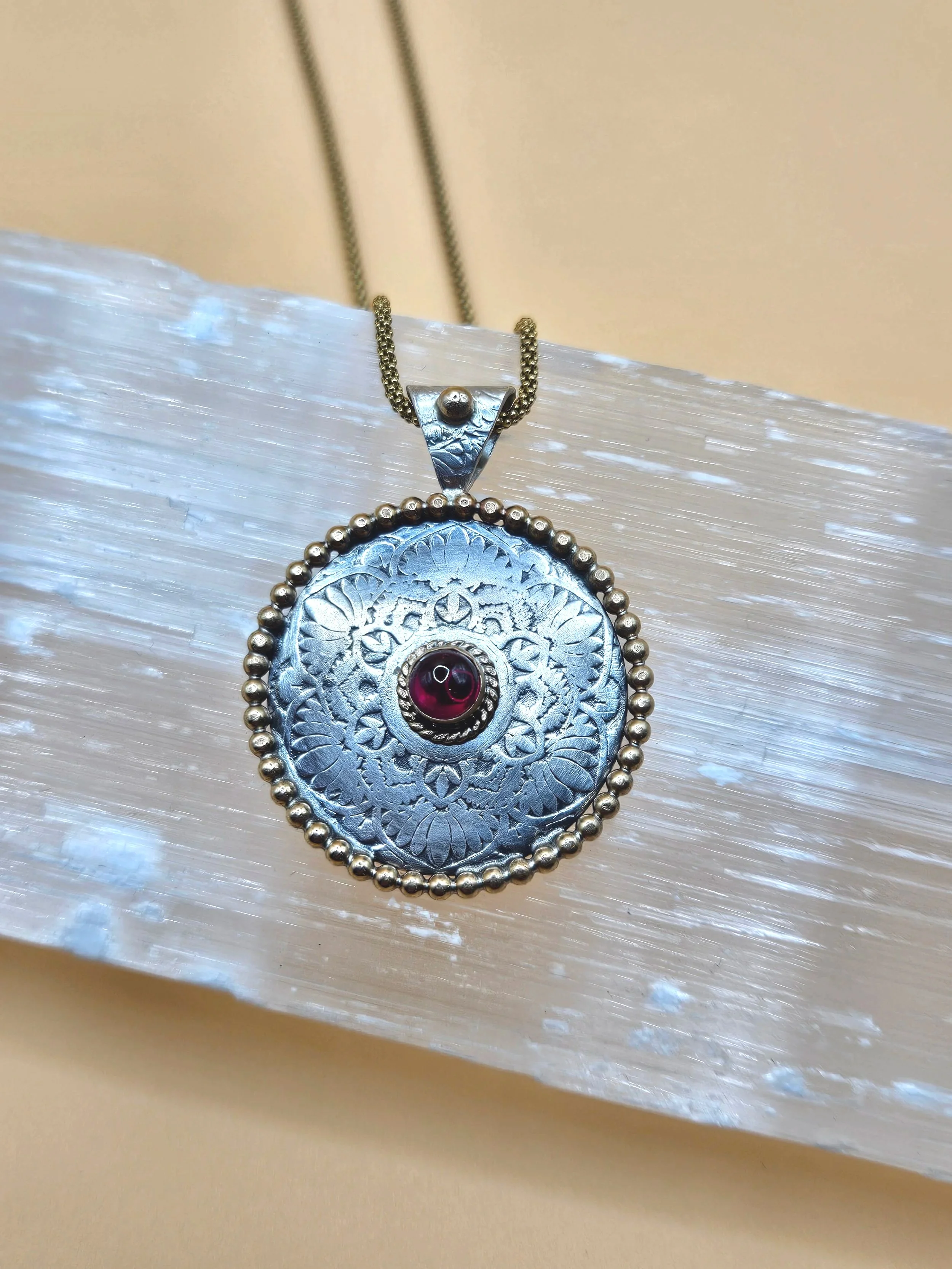 Sterling silver antiqued mandala pendant with genuine ruby and 14k gold accents.