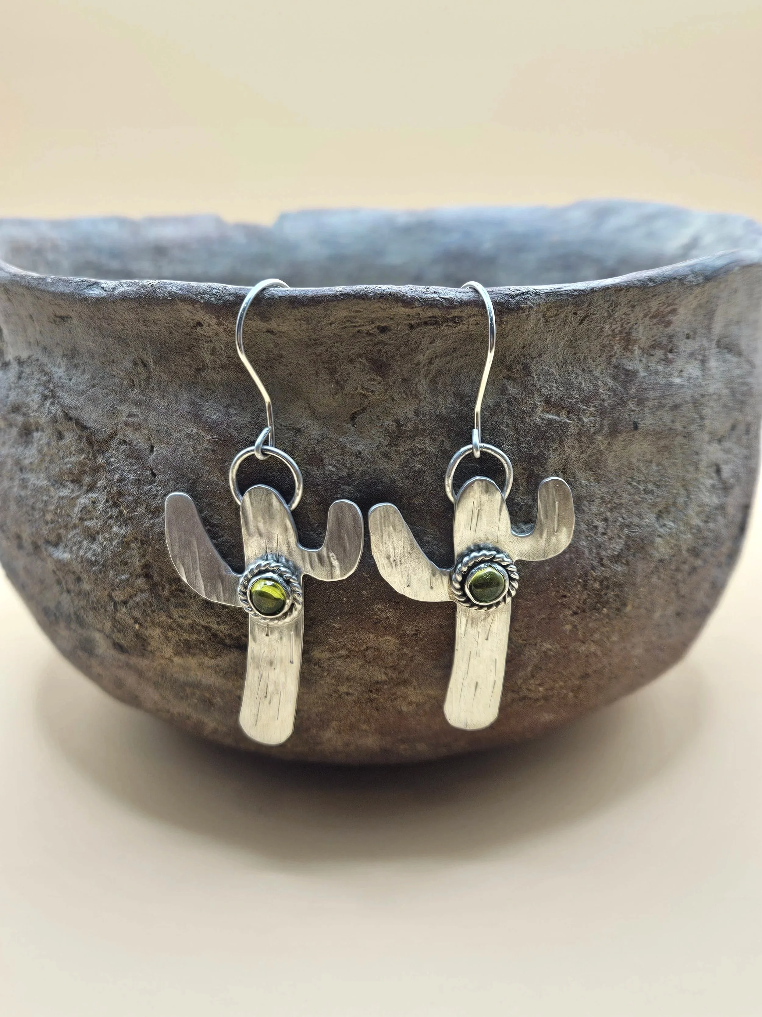 Sterling silver saguaro earrings with peridot gemstones and a rope boarder.