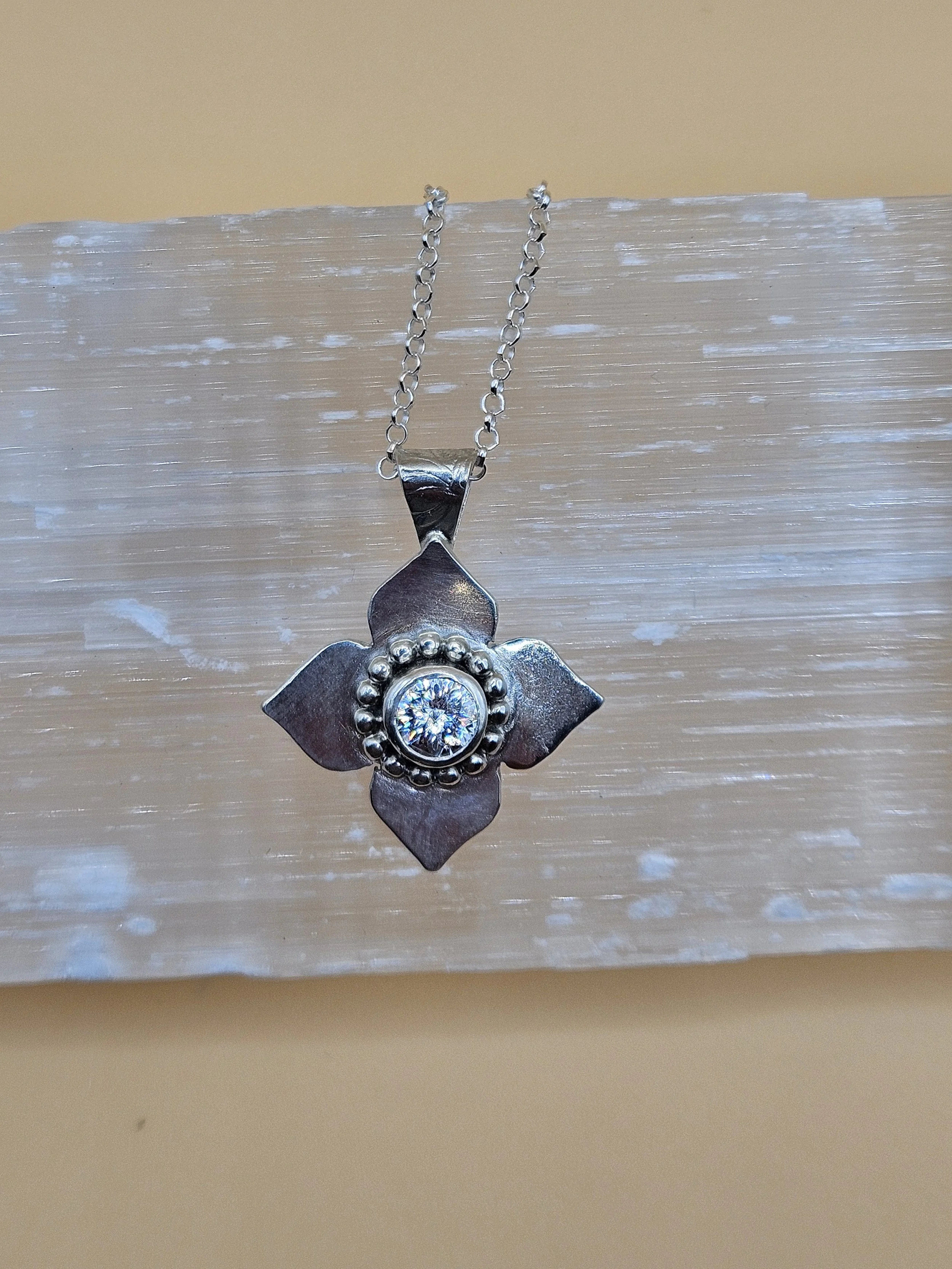 Sterling silver four petal flower pendant necklace with a one carat lab grown diamond solitaire stone.
