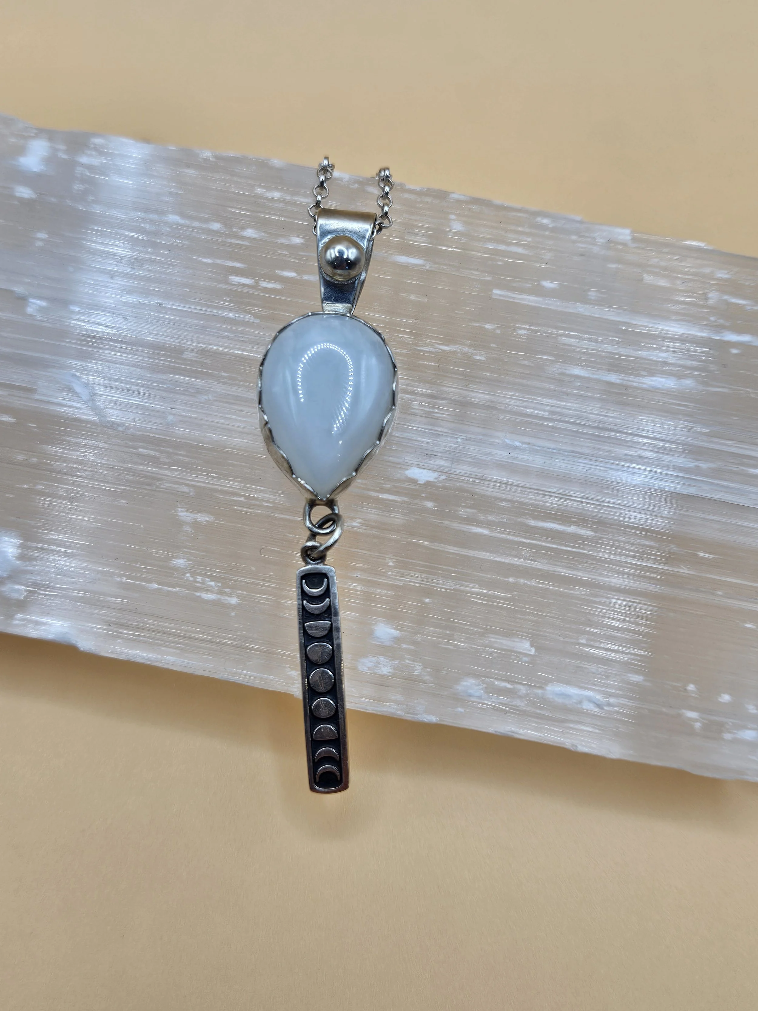 Sterling silver necklace with a teardrop-shaped pendant featuring a Moonstone and a moonphase drop charm.