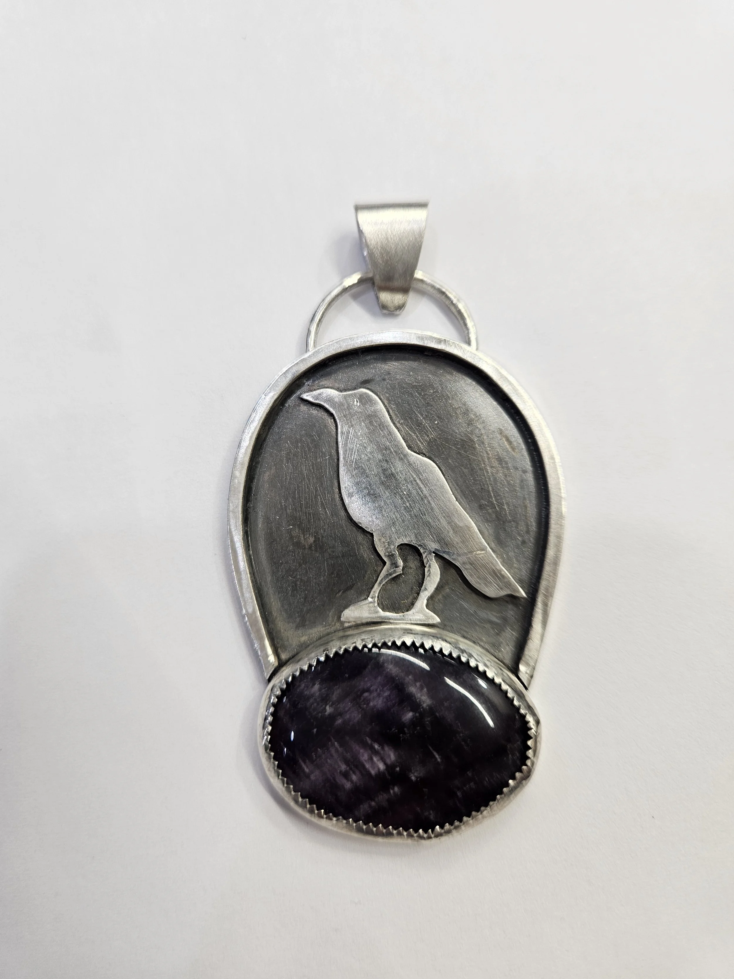 Sterling silver pendant with a resting Raven sitting a top an Amethyst gemstone.