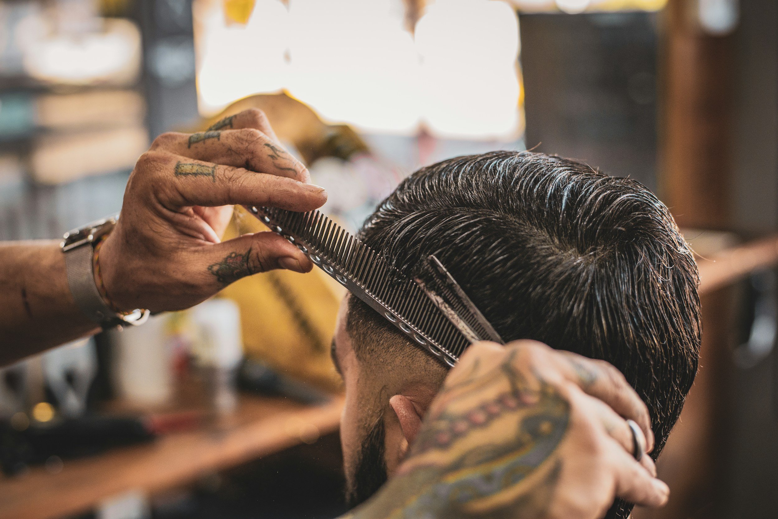 Barber trimming a man's hair with scissors and a comb in a barber shop.