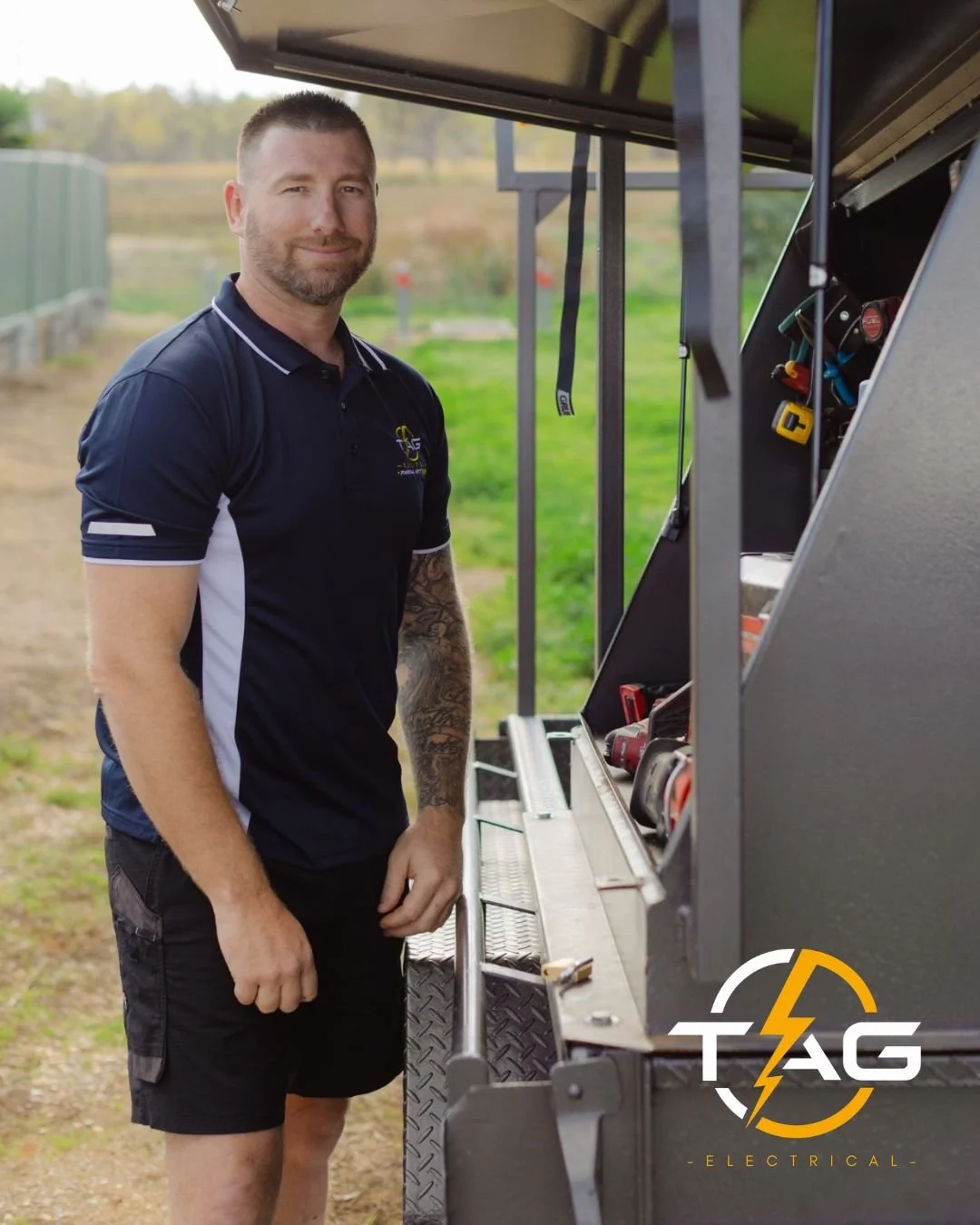 Trusted Wagga Wagga electrician, Trent Garner from TAG Electrical PWM,  standing next to his black utility trailer with TAG Electrical Logo.