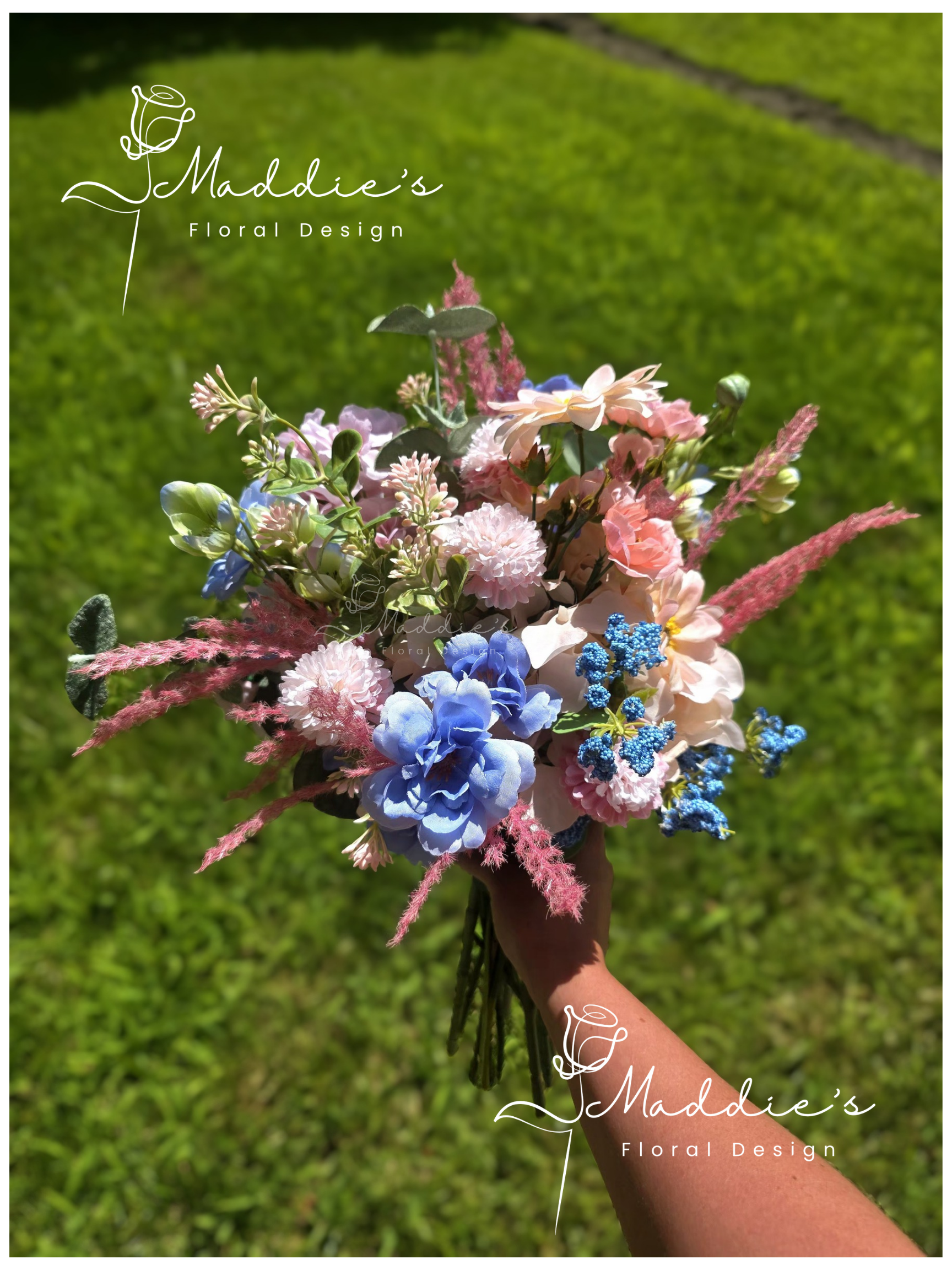 Hand holding a colorful bouquet of various flowers against a grassy background.