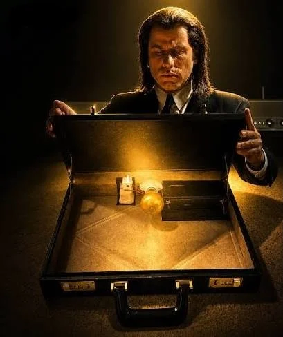 Stylized image of the John Travolta character in Quentin Tarantino's Pulp Fiction opening the legendary briefcase, which emits a gold glow. The audience never was told what was in the briefcase. The image shows the interior of the prop itself.