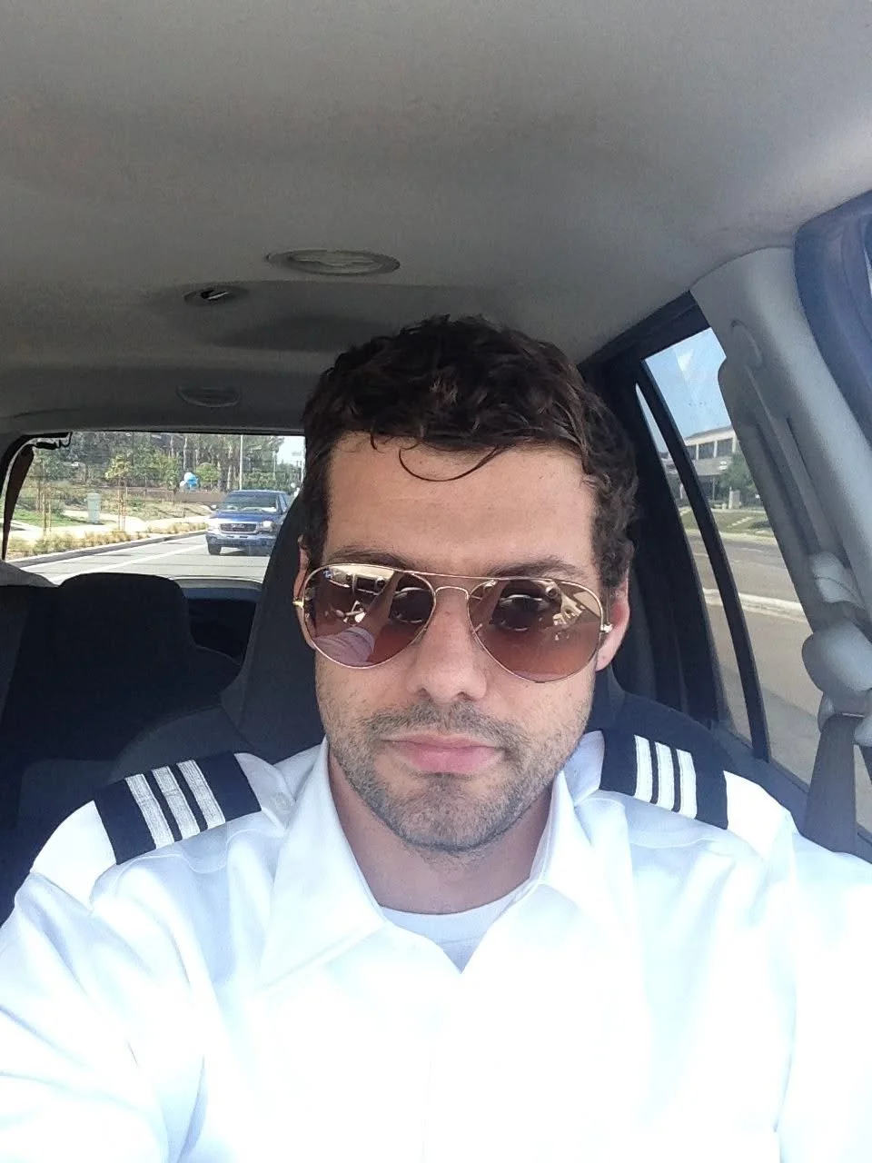 Max Schwartz proudly wearing his 3 -tripe pilot epaulets,  on his shoulders, while dressed in freshly pressed white's. He's driving to work at one of his first jobs as a flight instructor, in the aftermath of having graduated ATP Flight School.