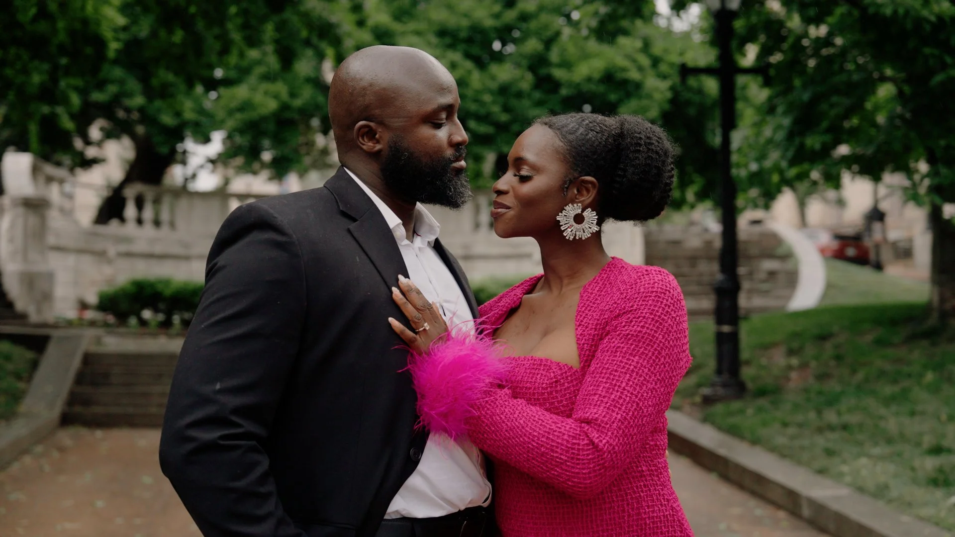 Liam and Moyo are standing close together outdoors during their engagement shoot.