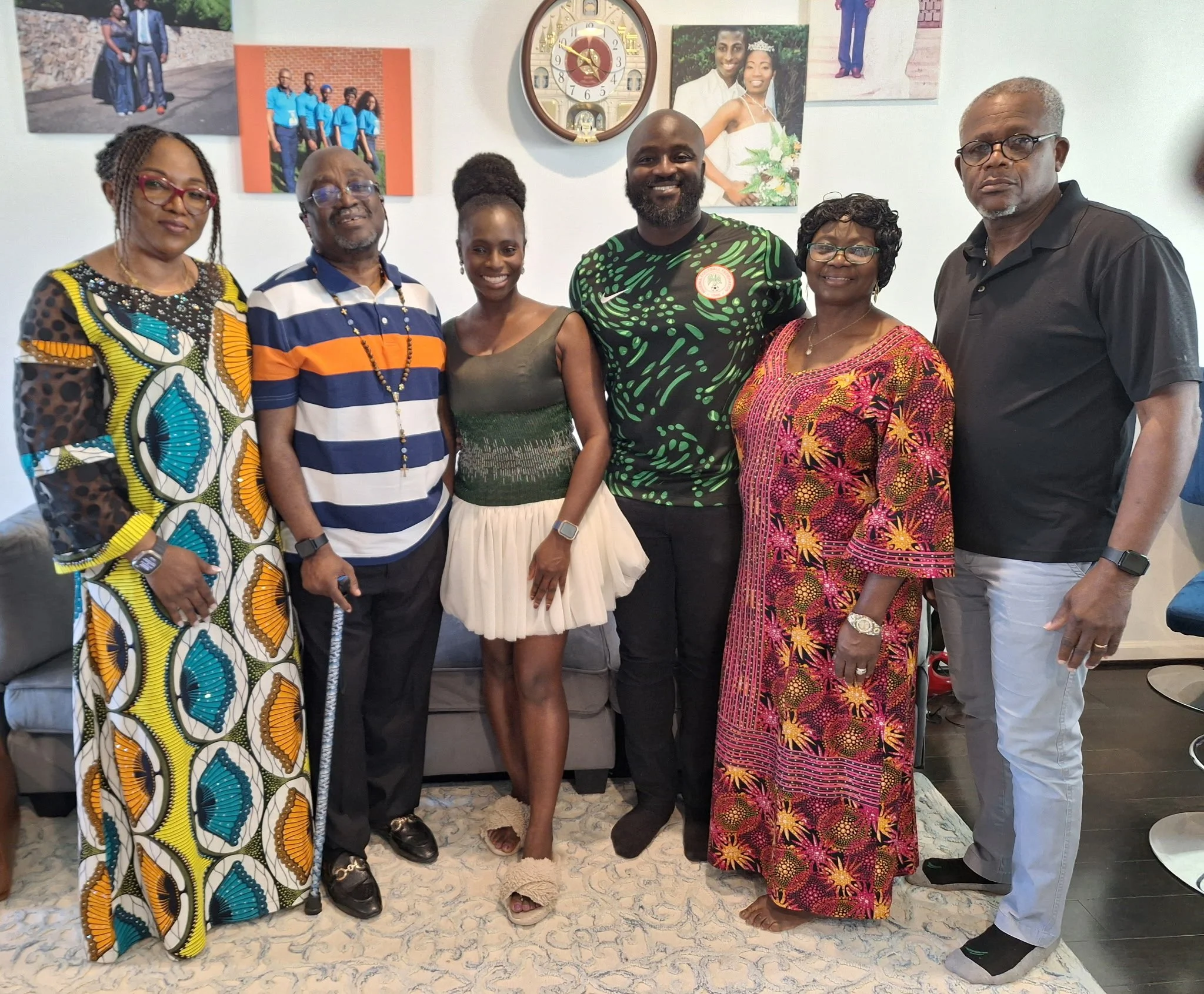 Liam and Moyo with their parents. They are dressed in colorful clothing, smiling, and standing close together.