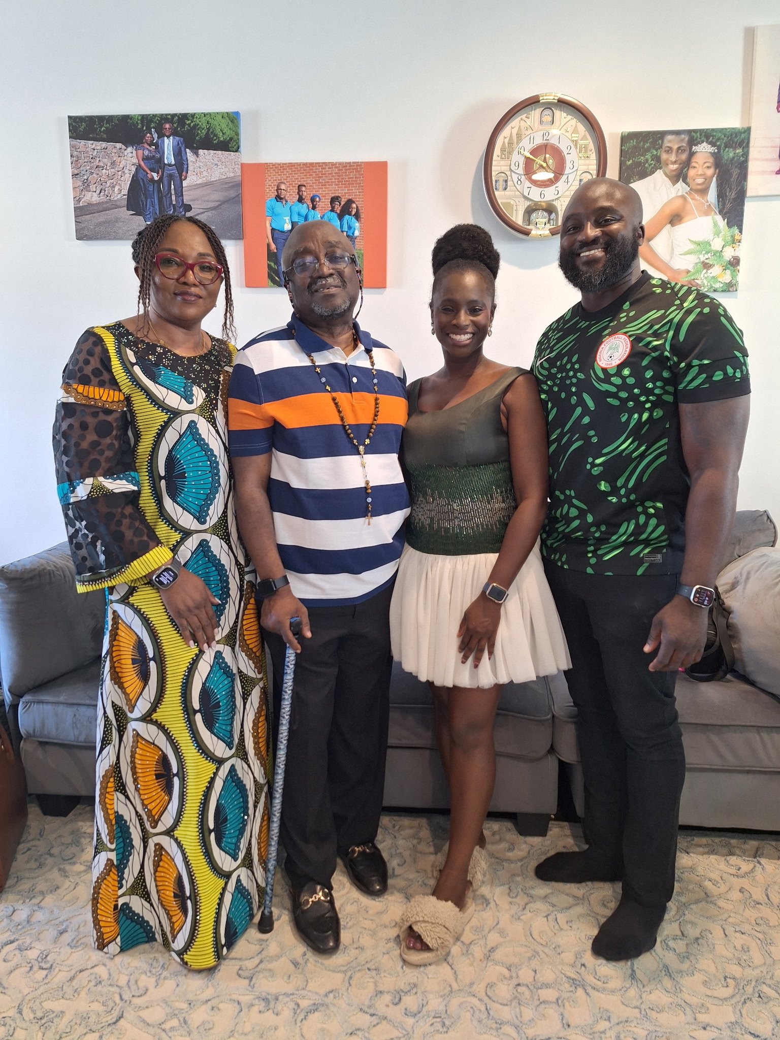 Moyo and Liam with Liam's parents. They are smiling and dressed in a mix of casual and formal attire.