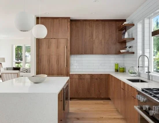 Modern kitchen with white countertops, grain matched cabinets, white subway tile backsplash.