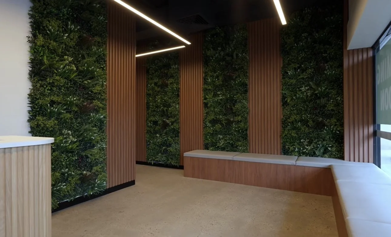 Modern interior space with green plant wall, wooden panel accents, beige seating, and large window.